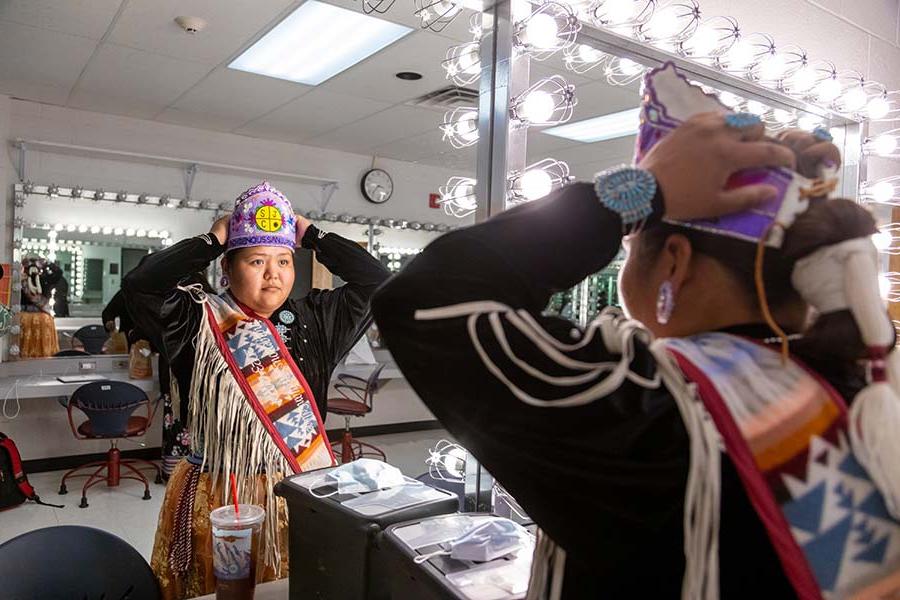 Contestant adjusts traditional regalia and headdress in dressing room before Ms. Indigenous San Juan College cultural pageant