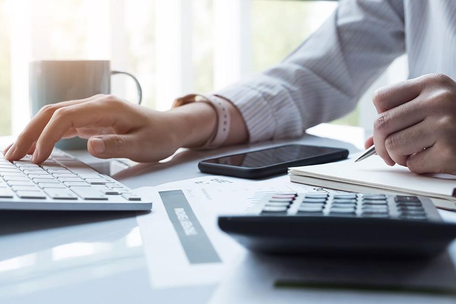 Accounting professional on calculator an laptop.